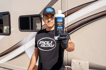 A man wearing a Poli Glow hat and Poli Glow shirt holding a bottle of Poli Glow in front of an RV