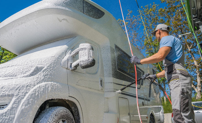 a man pressure washing off an RV that's covered in soap