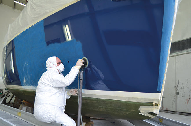 a man buffing a blue sailboat