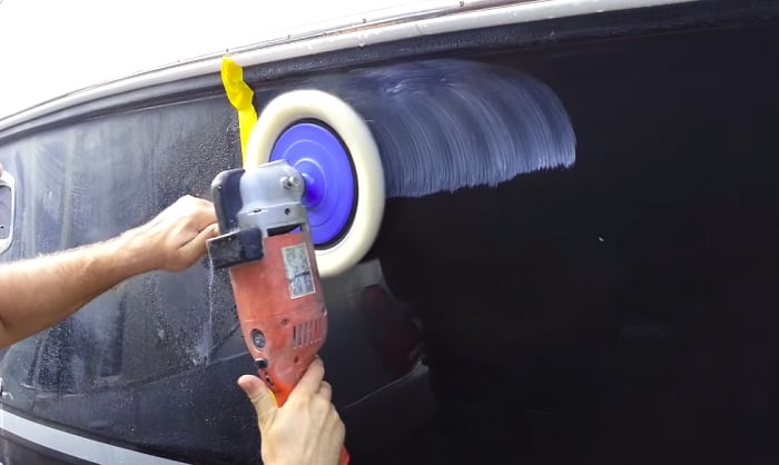 up close of a man buffing the hull of a black boat