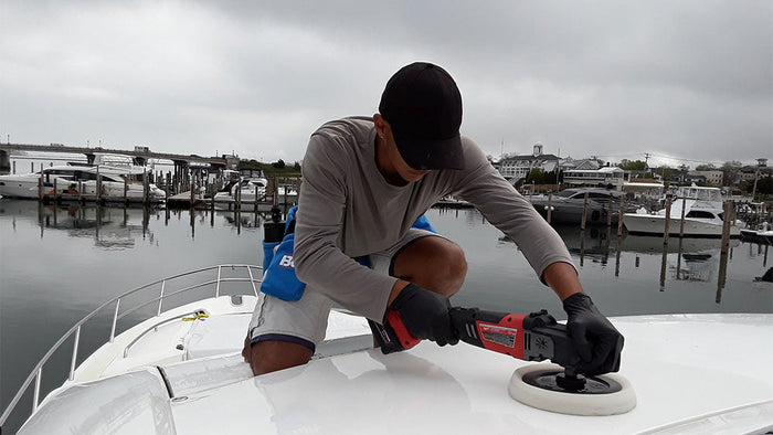 a man on top of a boat buffing out the surface