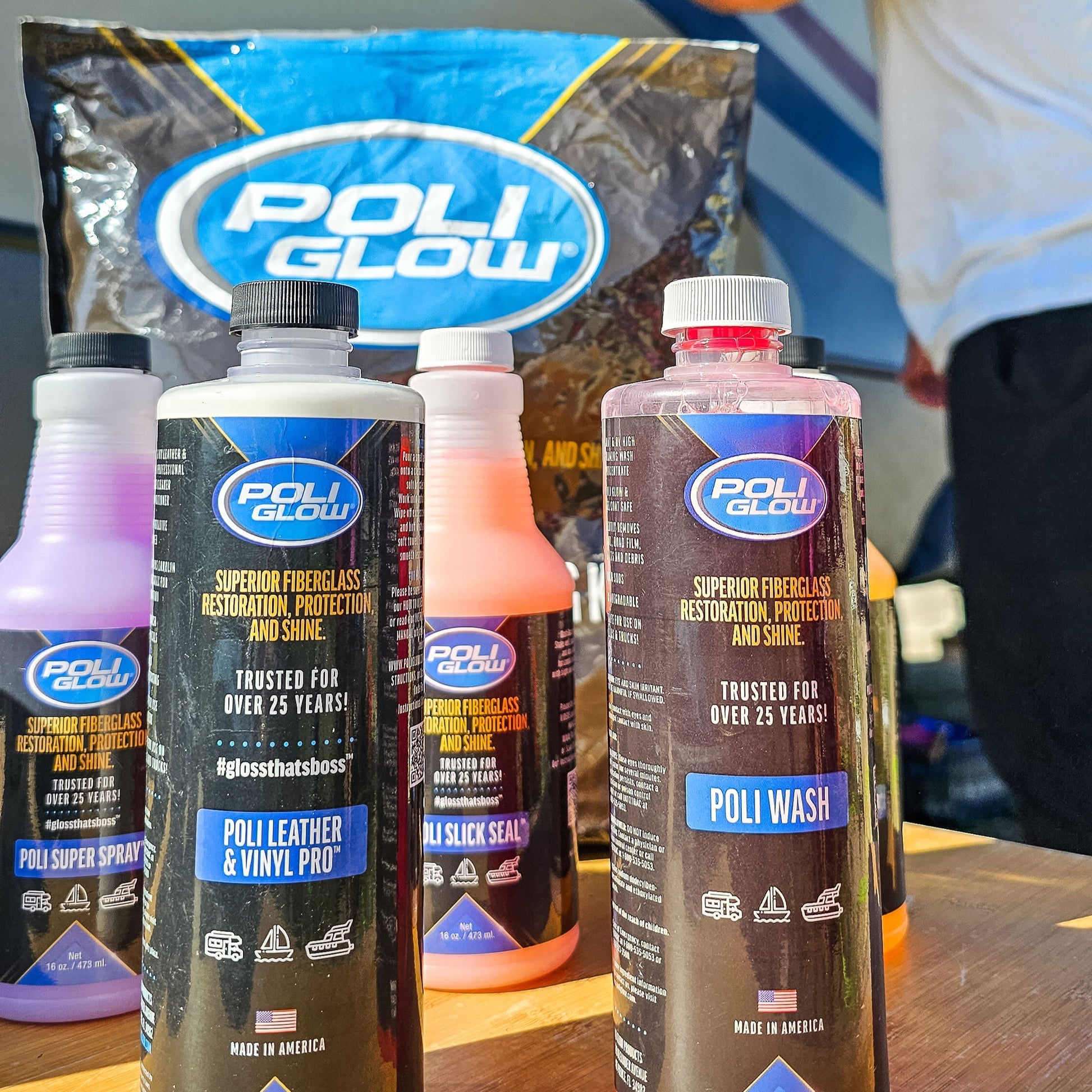 Poli Glow detailing kit featuring all the bottles displayed on a table with a male cleaning the dirt and grim from his RV.